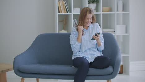 Portrait-of-happy-business-woman-enjoy-success-on-mobile-phone-at-home-office.-Closeup-joyful-girl-reading-good-news-on-phone-in-slow-motion.-Surprised-lady-celebrating-victory-on-phone-in-apartment.